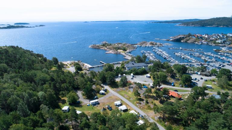 Bilde over Roligheden camping ovenfra med sjø, bobiler, båter og natur.