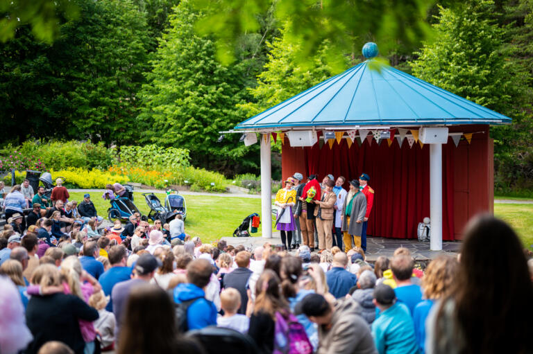 Byfest med folk og røvere ved byscenen i Kardemomme by, fullt av gjester.