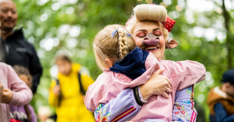 Klara på KuToppen smiler godt mens hun gir en varm klem til ei jente.