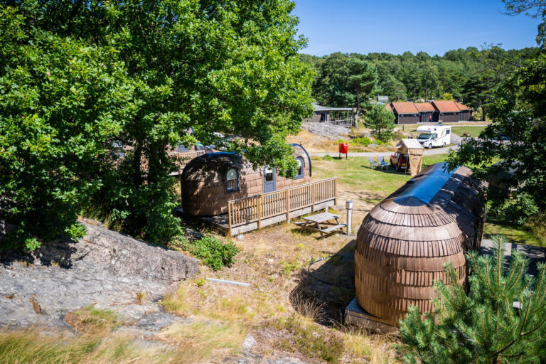 Roligheden Camping med noen hytter, benker bobil og telt.